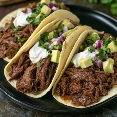 Delicious crock pot shredded beef tacos garnished with fresh toppings