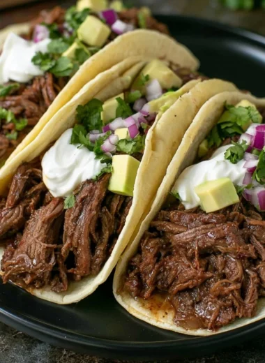 Delicious crock pot shredded beef tacos garnished with fresh toppings