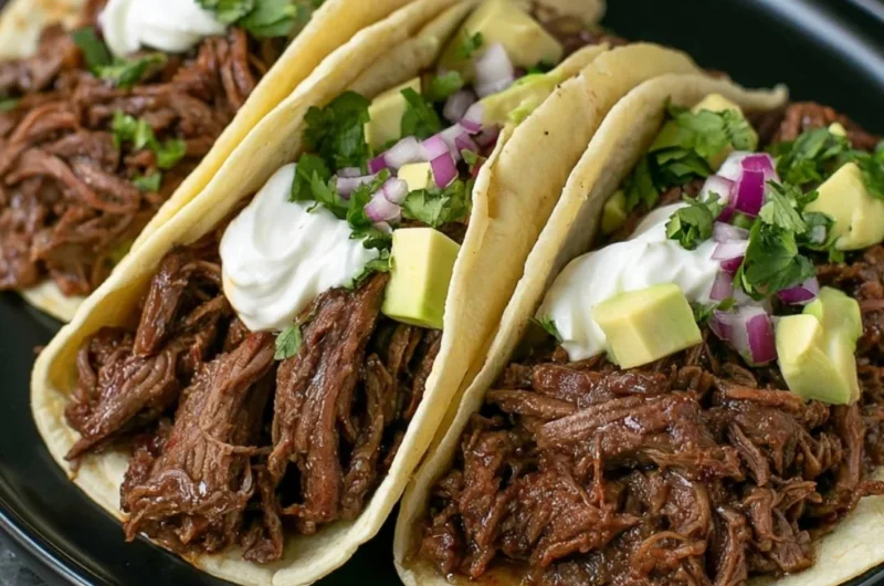 Delicious crock pot shredded beef tacos garnished with fresh toppings