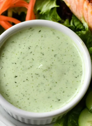 Creamy basil dressing served in a glass jar with fresh basil leaves.