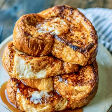 Delicious French toast topped with fresh berries and syrup on a cozy breakfast table.