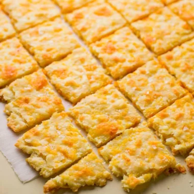 Cozy homemade sourdough crackers topped with cheddar cheese on a plate.