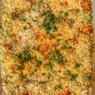 Cozy white bean and pesto bake topped with fresh herbs and cheese.
