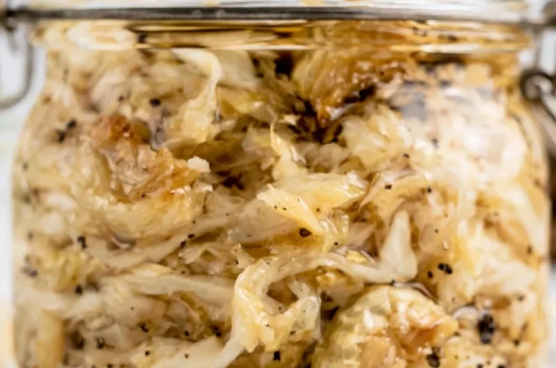 A jar of roasted garlic sauerkraut showcasing its vibrant color and texture.